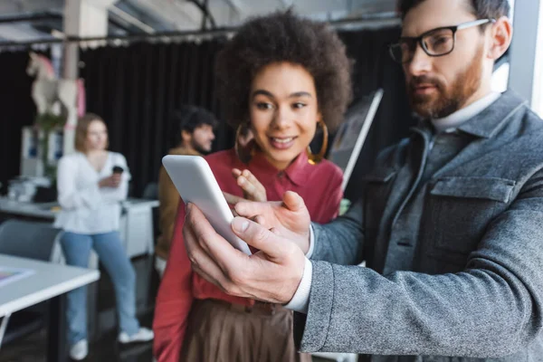 Gerente de publicidade em óculos mostrando telefone celular para mulher americana africana — Fotografia de Stock