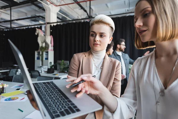 Werbemanager blicken auf Laptop neben multiethnischen Kollegen auf verschwommenem Hintergrund — Stockfoto