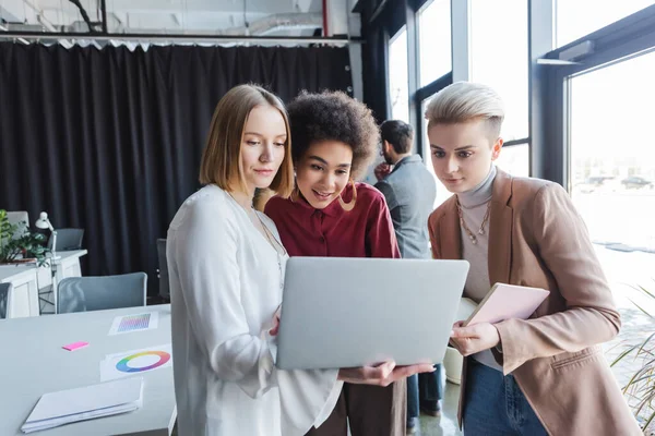 Multiethnic businesswomen looking at laptop in advertising agency — Stock Photo