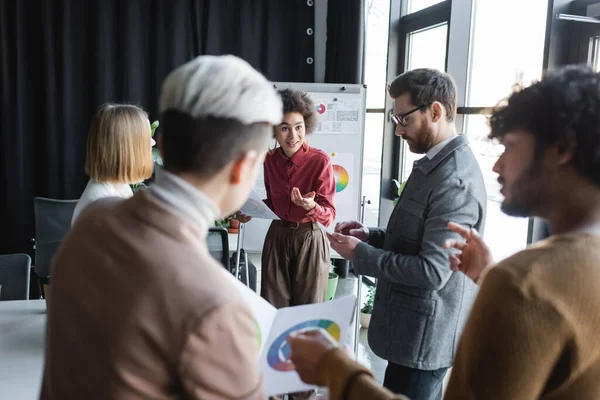 African american advertising manager pointing with finger while talking to interracial colleagues — Stock Photo