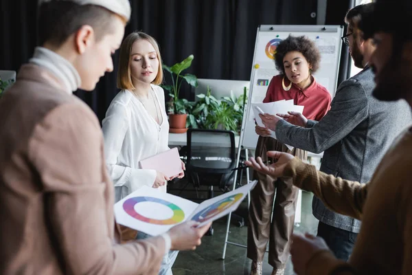 Uomo indiano offuscata puntando campioni di colore durante la discussione con colleghi multietnici in agenzia pubblicitaria — Foto stock