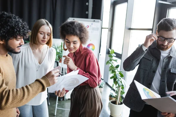 Designer pubblicitari multietnici che guardano carte con campioni di colore in ufficio — Foto stock