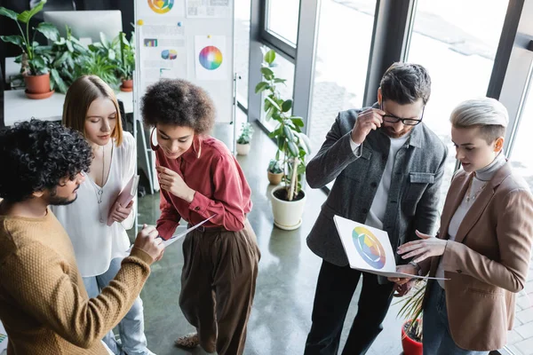 Vista de ángulo alto de los gerentes multiculturales que miran muestras de color en la agencia de publicidad - foto de stock