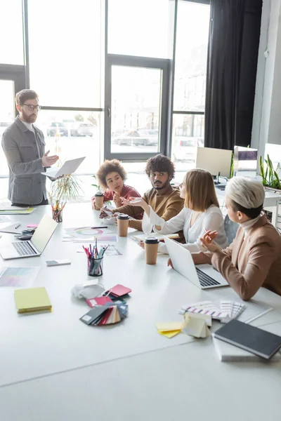 Gestionnaires de publicité multiethnique parlant lors d'une réunion au bureau — Photo de stock