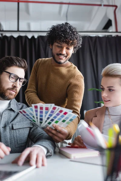 Alegre indio diseñador de publicidad mostrando muestras de color a los colegas - foto de stock