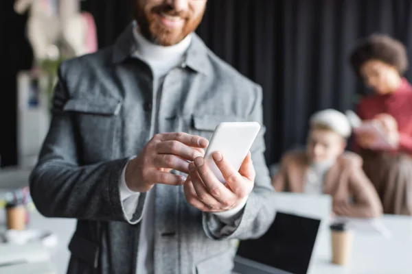 Ausgeschnittener Blick auf verschwommenen Geschäftsmann mit Smartphone in Werbeagentur — Stockfoto