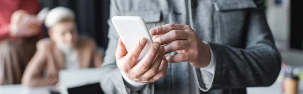 Vista parcial del hombre que usa el teléfono móvil en la agencia de anuncios sobre fondo borroso, banner - foto de stock