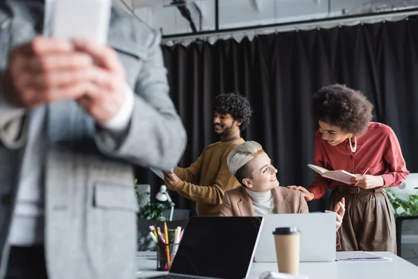 Happy african american woman with notebook talking to advertising manager in office — Stock Photo