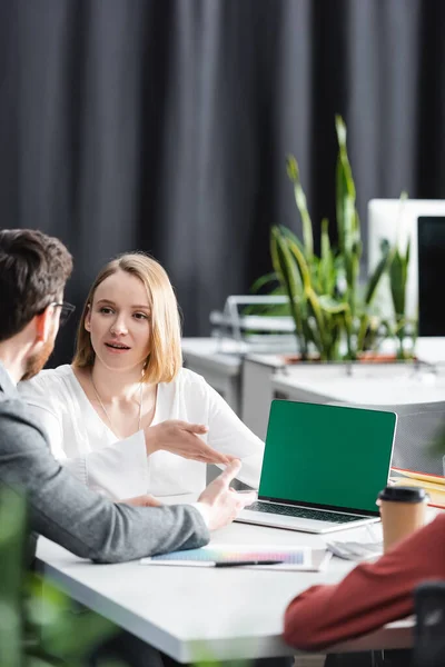 Gestionnaires pointant vers ordinateur portable avec écran vert tout en parlant en agence de publicité — Photo de stock