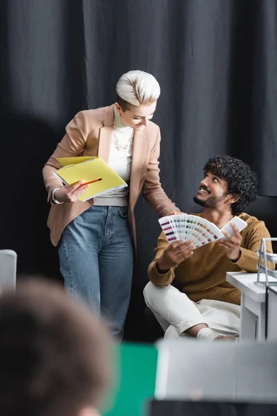 Gerente de publicidade falando com designer indiano sentado com telefone celular e amostras de cor — Fotografia de Stock