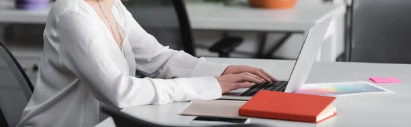 Vista parcial de la mujer escribiendo en el ordenador portátil en la agencia de publicidad, bandera - foto de stock