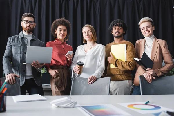 Positives multiethnisches Team einer Werbeagentur blickt in die Kamera im Büro — Stockfoto