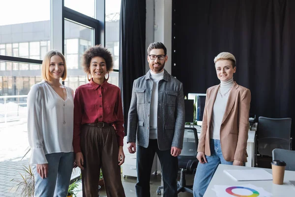 Erfolgreiche multikulturelle Geschäftsleute lächeln in Werbeagentur in die Kamera — Stockfoto