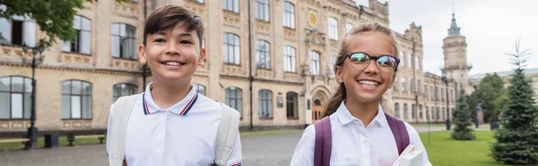 Happy interracial schoolkids with backpacks standing outdoors, banner — Stock Photo