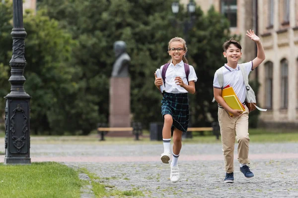 Азиатский школьник держит блокноты рядом с другом на улице — стоковое фото