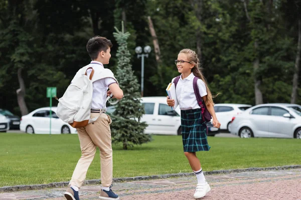Позитивні багатоетнічні школярі з блокнотами, що виходять на вулицю — стокове фото