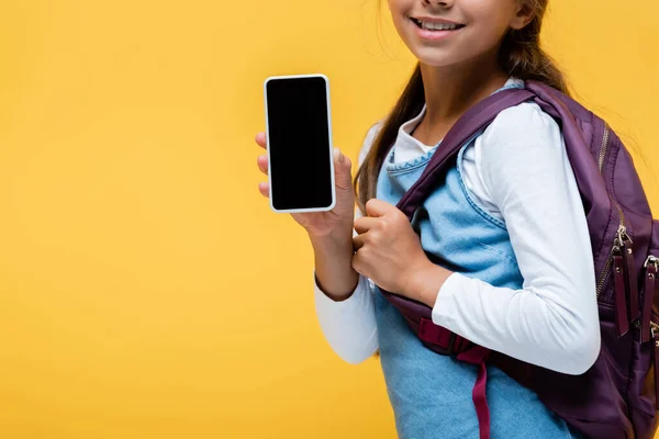 Обрізаний вид усміхненого школяра, що тримає смартфон ізольовано на жовтому — стокове фото