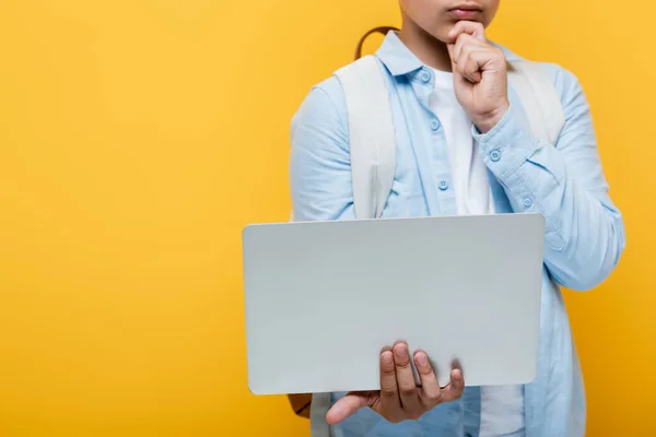 Cropped view of schoolkid holding laptop isolated on yellow — Stock Photo