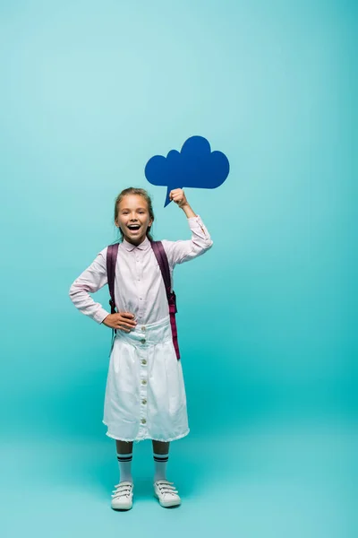 Alegre colegiala celebración pensamiento burbuja sobre fondo azul - foto de stock