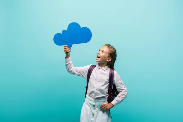 Excited schoolkid looking at thought bubble isolated on blue — Stock Photo