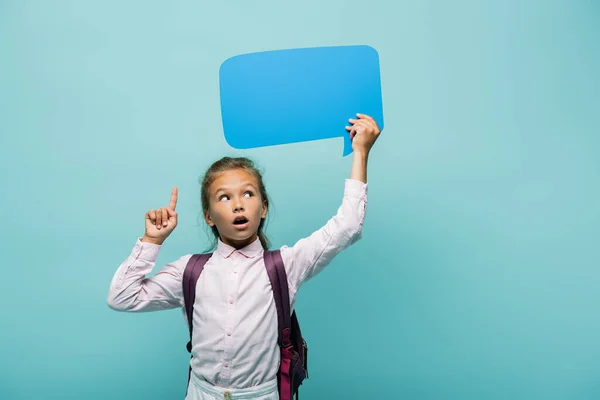 Colegial pensativo teniendo idea y sosteniendo la burbuja del habla aislado en azul - foto de stock