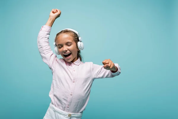 Веселий школяр слухає музику в навушниках ізольовано на синьому — стокове фото
