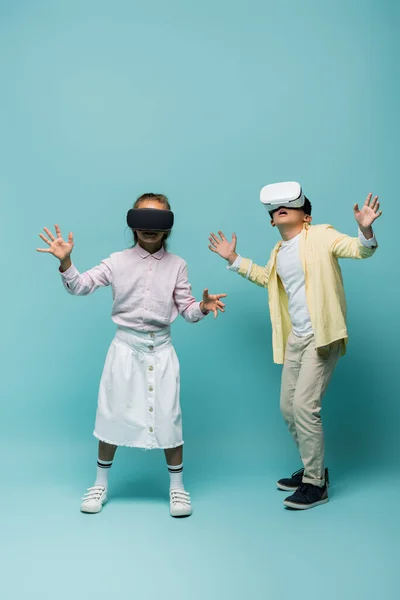 Niños en auriculares vr de pie sobre fondo azul - foto de stock