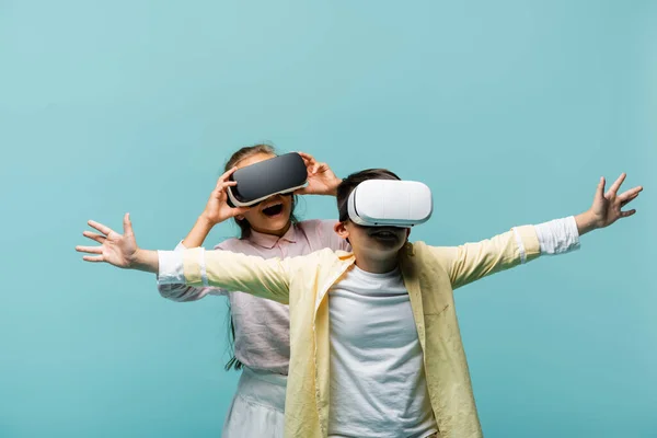 Positive preteen kids in vr headsets spielen Videospiel isoliert auf blau — Stockfoto