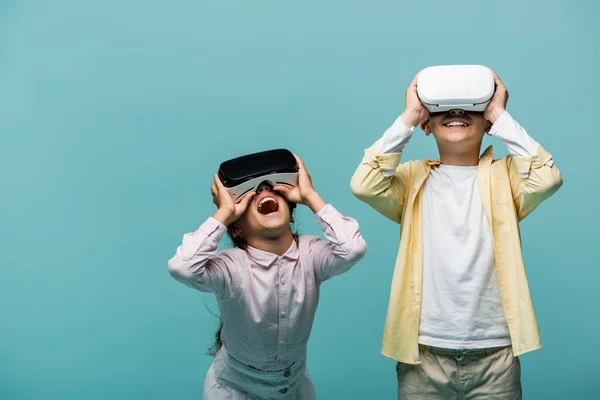 Niños preadolescentes emocionados jugando videojuegos en auriculares vr aislados en azul - foto de stock