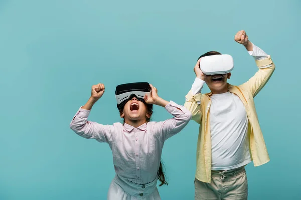 Excited preteen friends using vr headsets isolated on blue — Stock Photo