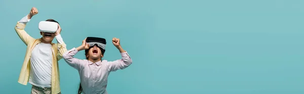 Excited kids playing video game in vr headset and showing yes gesture on blue background, banner — Stock Photo