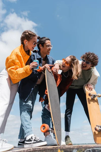 Riant amis regardant asiatique patineur grimacing et pointant avec doigt à l'extérieur — Photo de stock