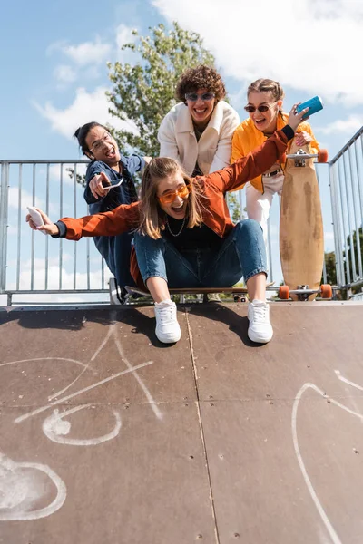 Excitée femme hurlant sur la rampe de skate près souriant interracial amis — Photo de stock