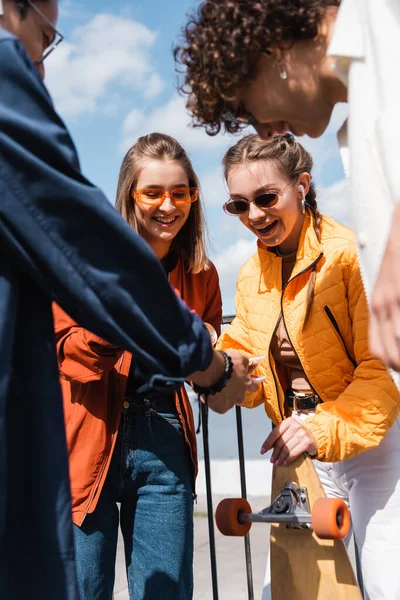 Cheerful interracial friends connecting smartphones while spending time outdoors — Stock Photo