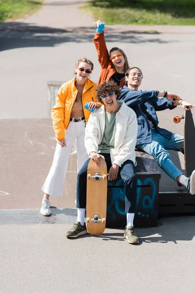 Patineurs multiethniques à la mode et heureux regardant la caméra en plein air — Photo de stock