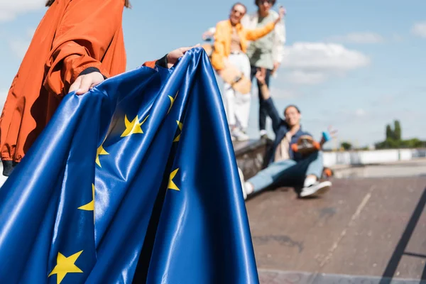 Vue partielle de la femme avec drapeau de l'union européenne près des amis flous à l'extérieur — Photo de stock