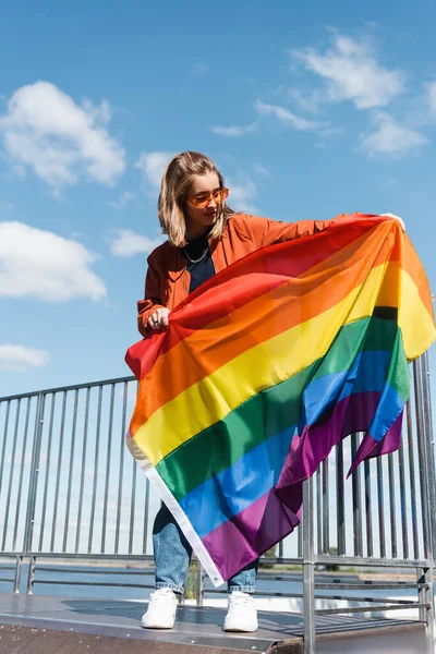 Comprimento total da jovem de pé com bandeira lgbt perto de cerca — Fotografia de Stock