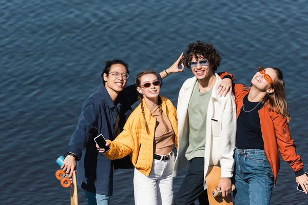 Feliz asiático homem mostrando vitória sinal perto elegante multiétnico amigos — Fotografia de Stock