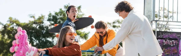 Amici multietnici in movimento carrello della spesa con donna allegra in pattini a rotelle, banner — Foto stock