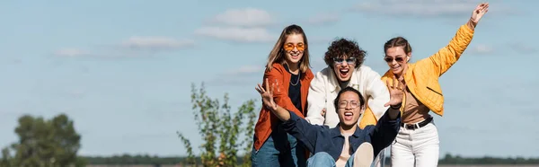 Excité asiatique homme crier tout en s'amusant avec des amis à l'extérieur, bannière — Photo de stock