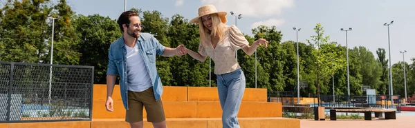 Smiling man holding hand of girlfriend in skate park, banner — Stock Photo