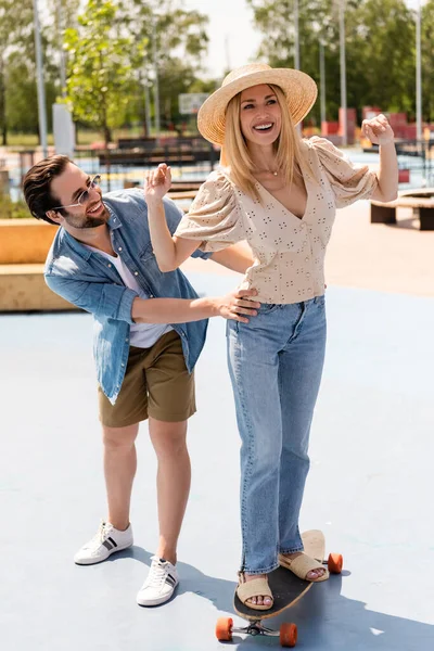 Cheerful couple riding longboard in skate park at daytime — Stock Photo