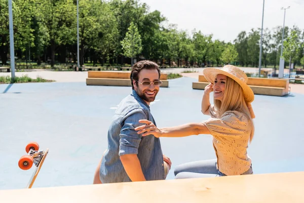 Coppia sorridente trascorrere del tempo vicino longboard in skate park — Foto stock