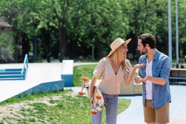 Vista laterale di coppia positiva con longboard parlando in skate park — Foto stock