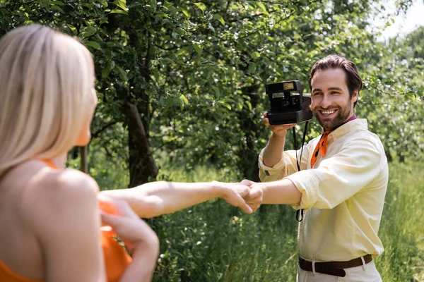 El hombre a la moda la celebración de la cámara retro y la mano de novia borrosa en el parque - foto de stock