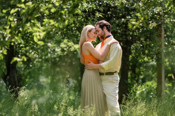 Side view of fashionable couple embracing in summer park — Stock Photo