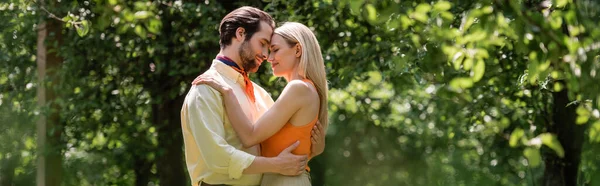 Vista lateral de la pareja romántica de moda abrazándose en el parque de verano, pancarta - foto de stock