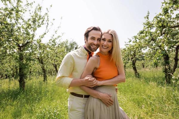 Trendy couple holding hands and looking at camera in summer park — Stock Photo