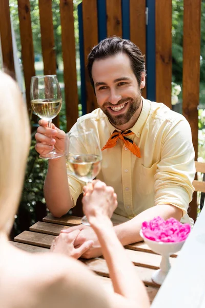 Стильный мужчина держит бокал вина и руку подруги в кафе на открытом воздухе — стоковое фото