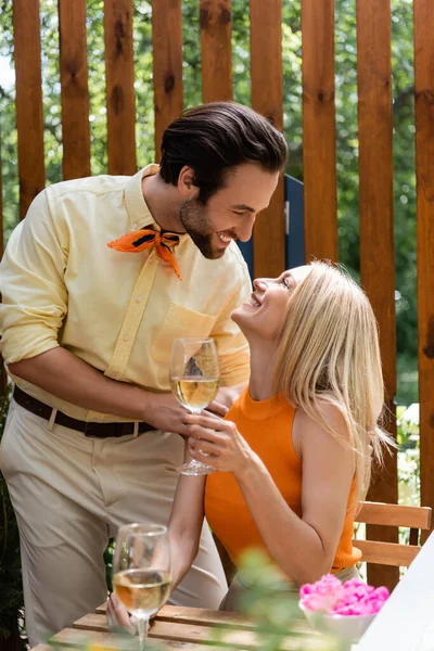 Vista lateral do casal elegante olhando uns para os outros perto do vinho no café ao ar livre — Fotografia de Stock